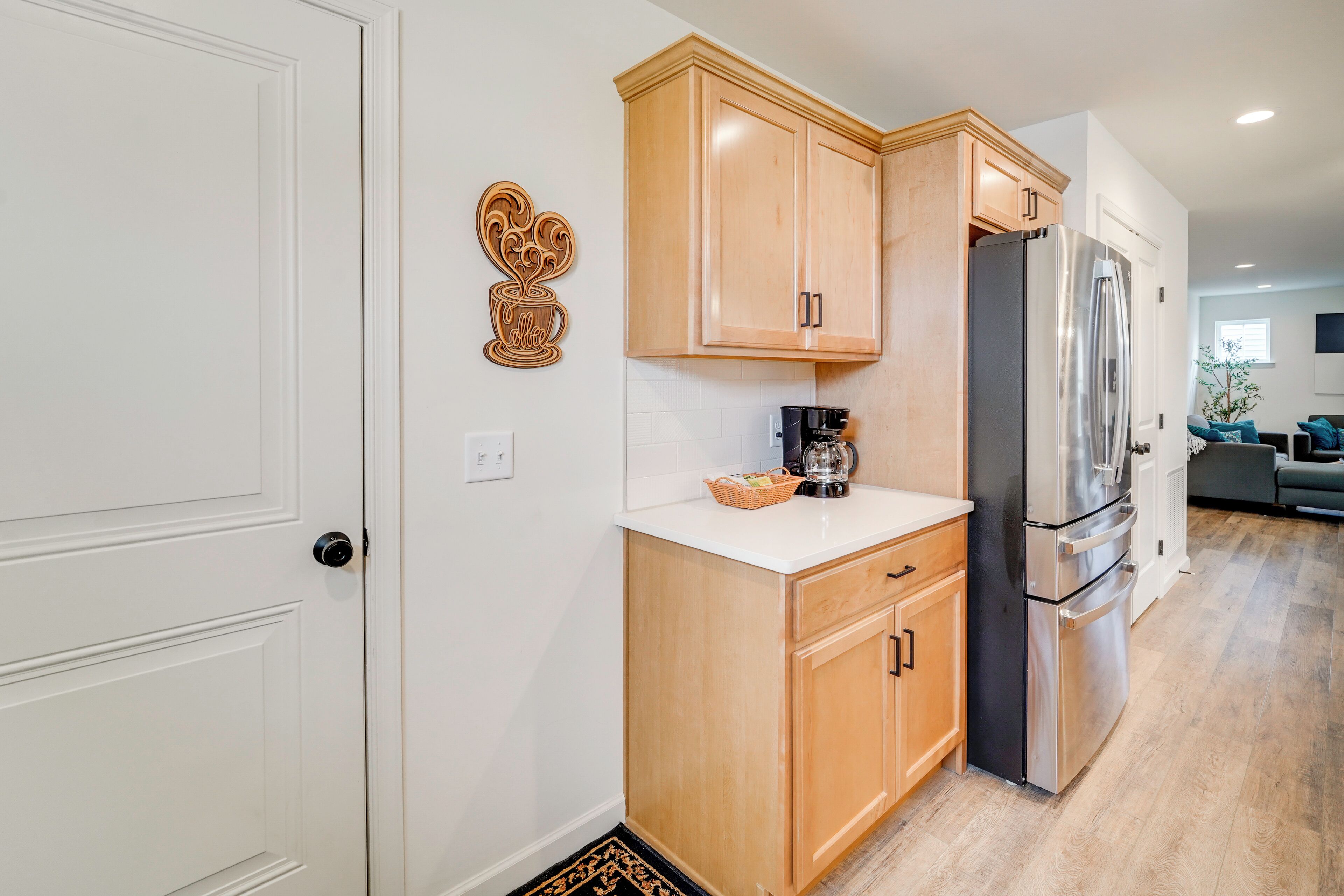 Una cocina moderna con armarios de madera, un refrigerador de acero inoxidable y una encimera blanca.