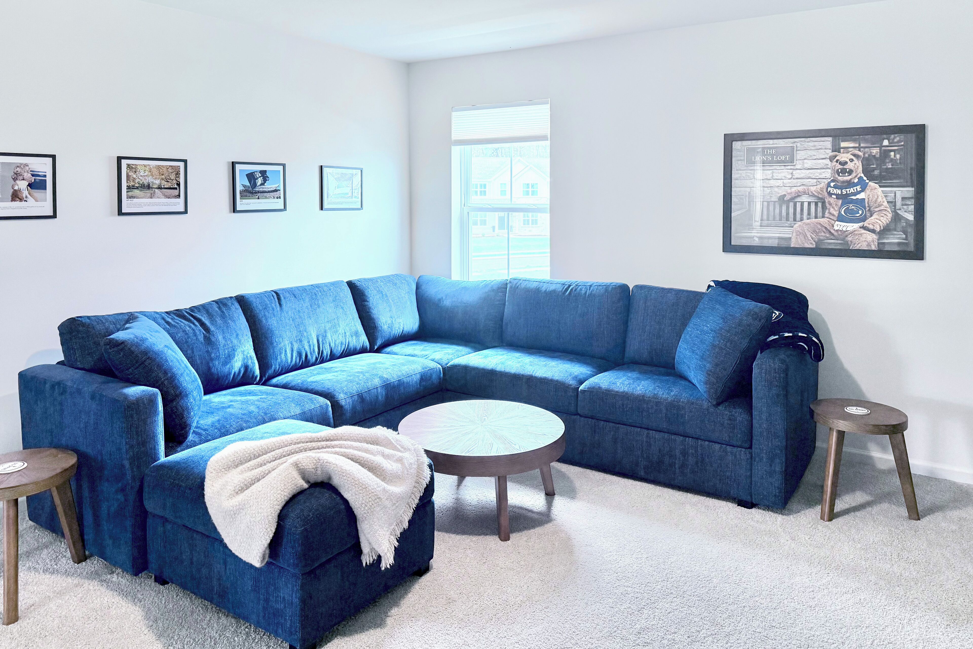 A modern living room with a blue sectional sofa, a round coffee table, and a small side table.