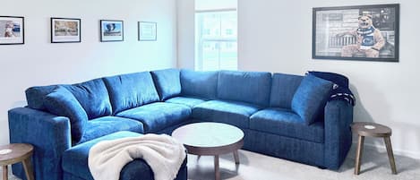 A modern living room with a blue sectional sofa, a round coffee table, and a small side table.