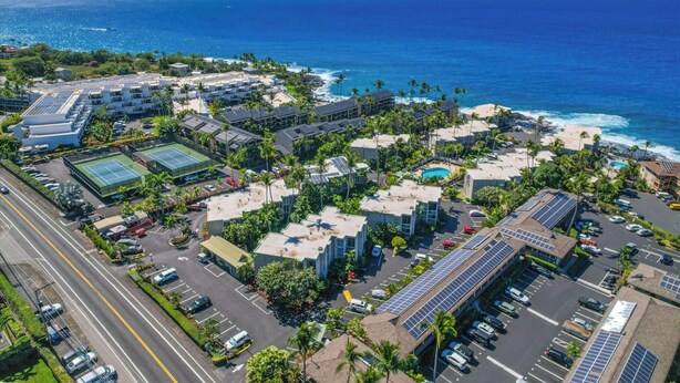 An aerial view of a coastal hotel complex with multiple buildings, parking areas, and a view of the ocean. - Top Floor Oceanfront Condominium in Kailua-kona (Kailua-Kona)