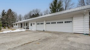 A single-story building with a garage, a porch, and a small front yard with snow.