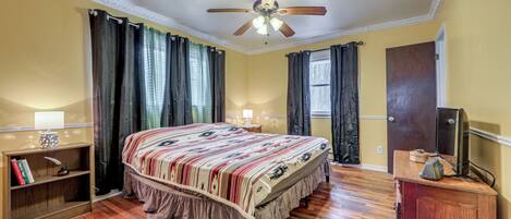A bedroom with a bed, a ceiling fan, a nightstand, a bookshelf, and a dresser.