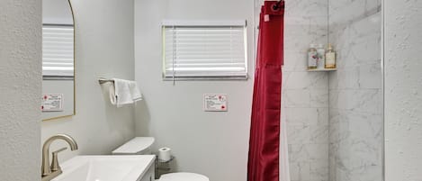 Un baño con lavamanos blanco, inodoro y cortina de ducha.