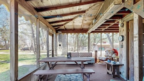 Un espace extérieur abrité, équipé de tables de pique-nique, de bancs et d’un tapis à motifs.