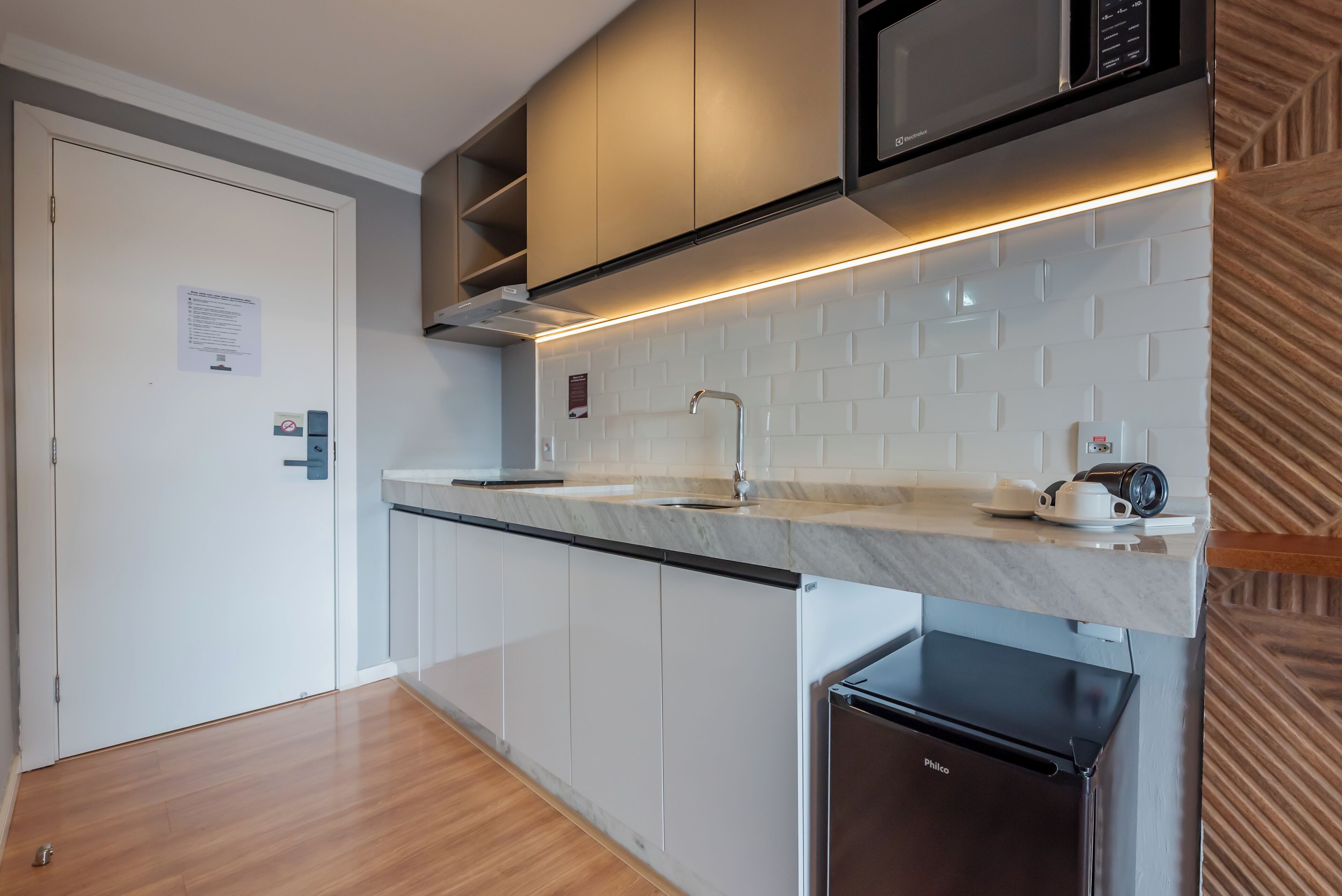A modern kitchen with a built-in microwave, a sink, and a compact refrigerator.