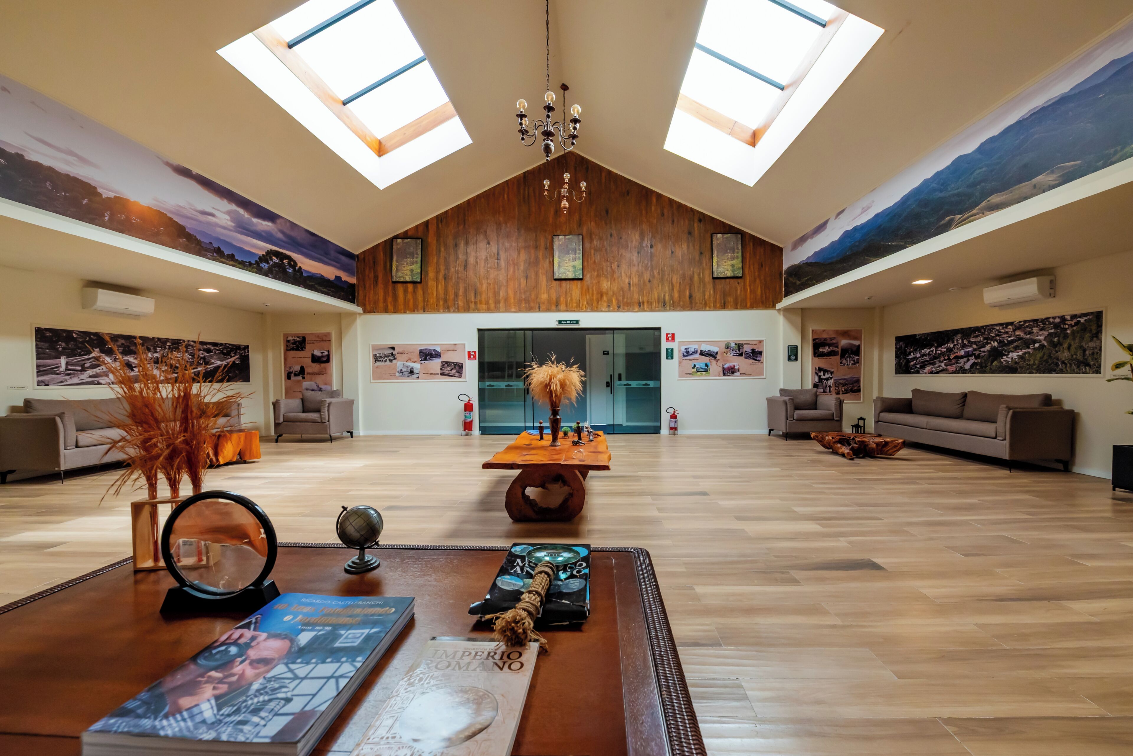 A spacious lobby with high ceilings, skylights, a chandelier, and a central table with various items.