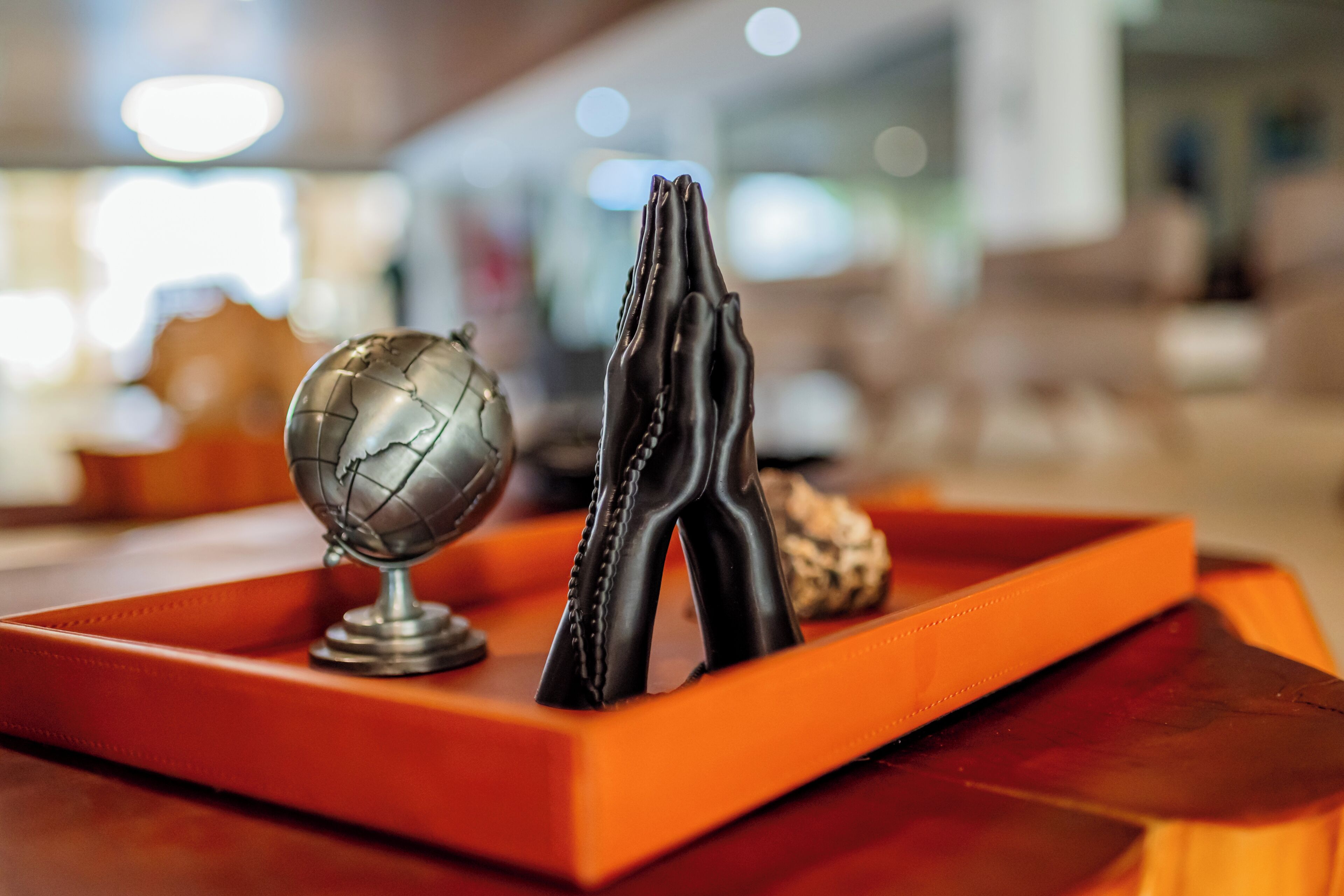A wooden table with a globe and a pair of black leather gloves.