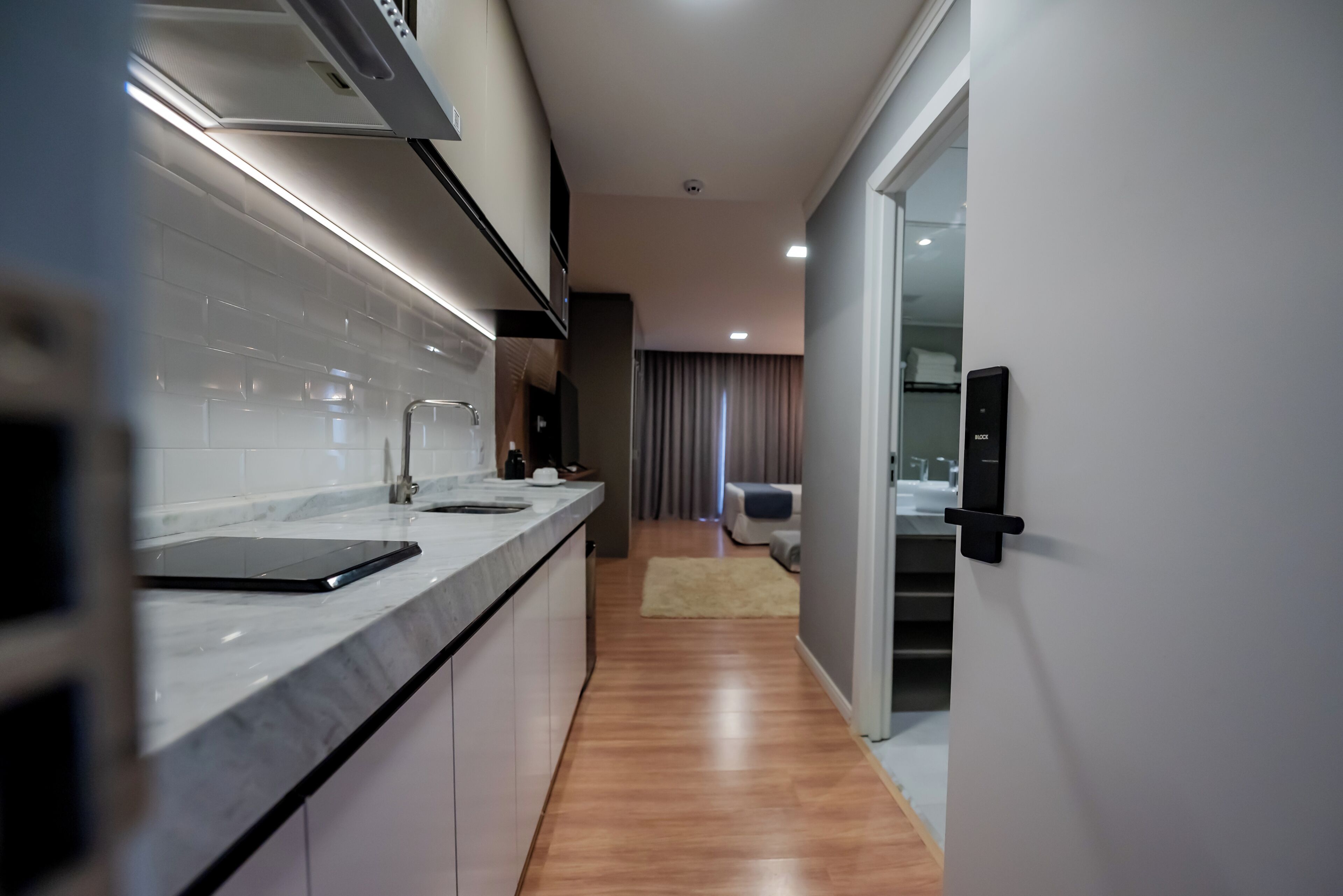 A modern kitchen with a marble countertop, a built-in oven, and a sliding door leading to a living area.
