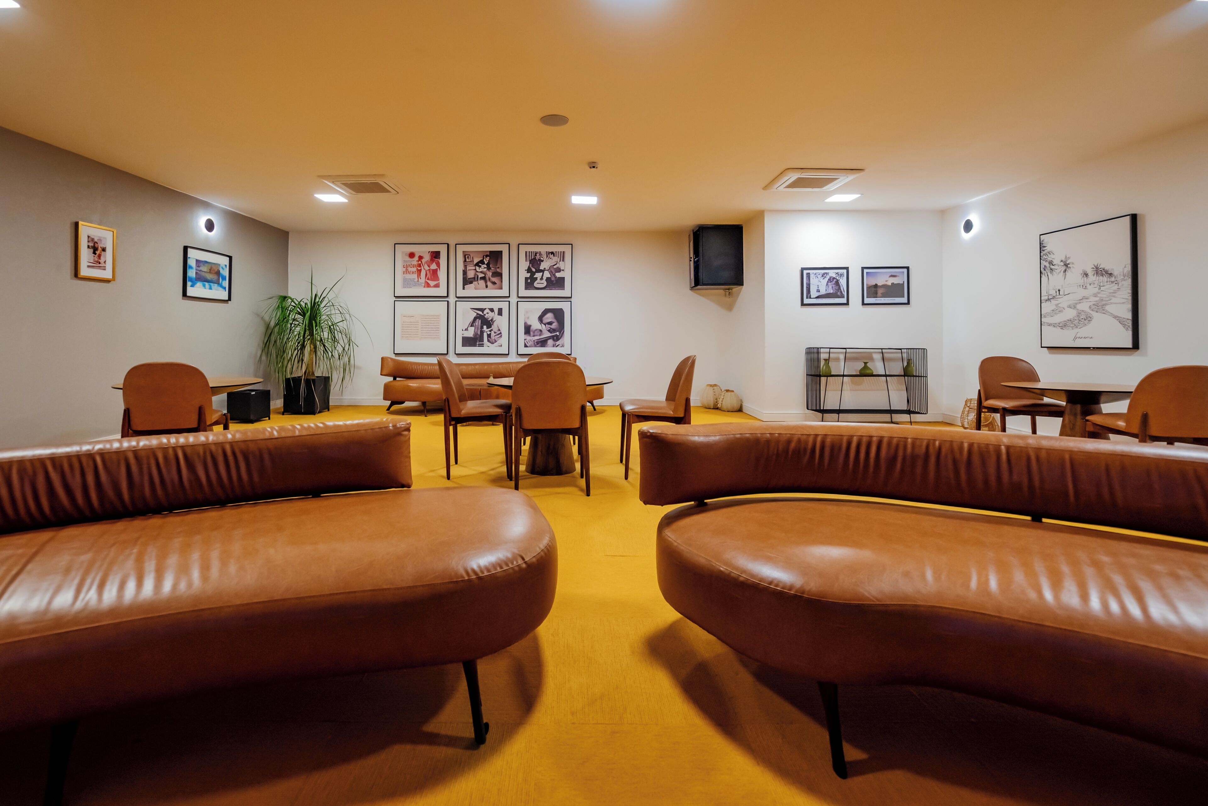A conference room with brown leather sofas, a table, chairs, and framed pictures on the walls.