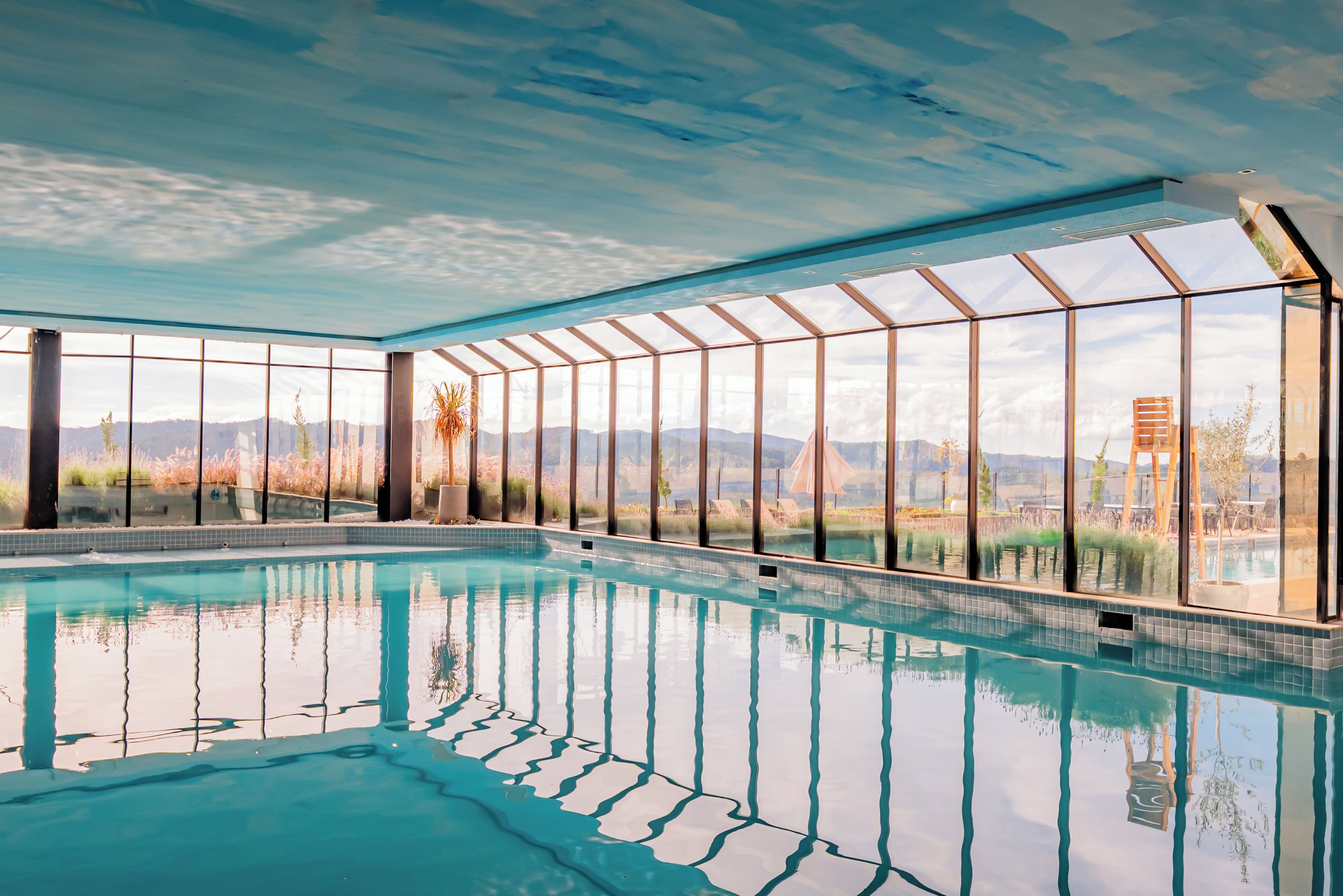 A swimming pool with a glass ceiling and large windows.