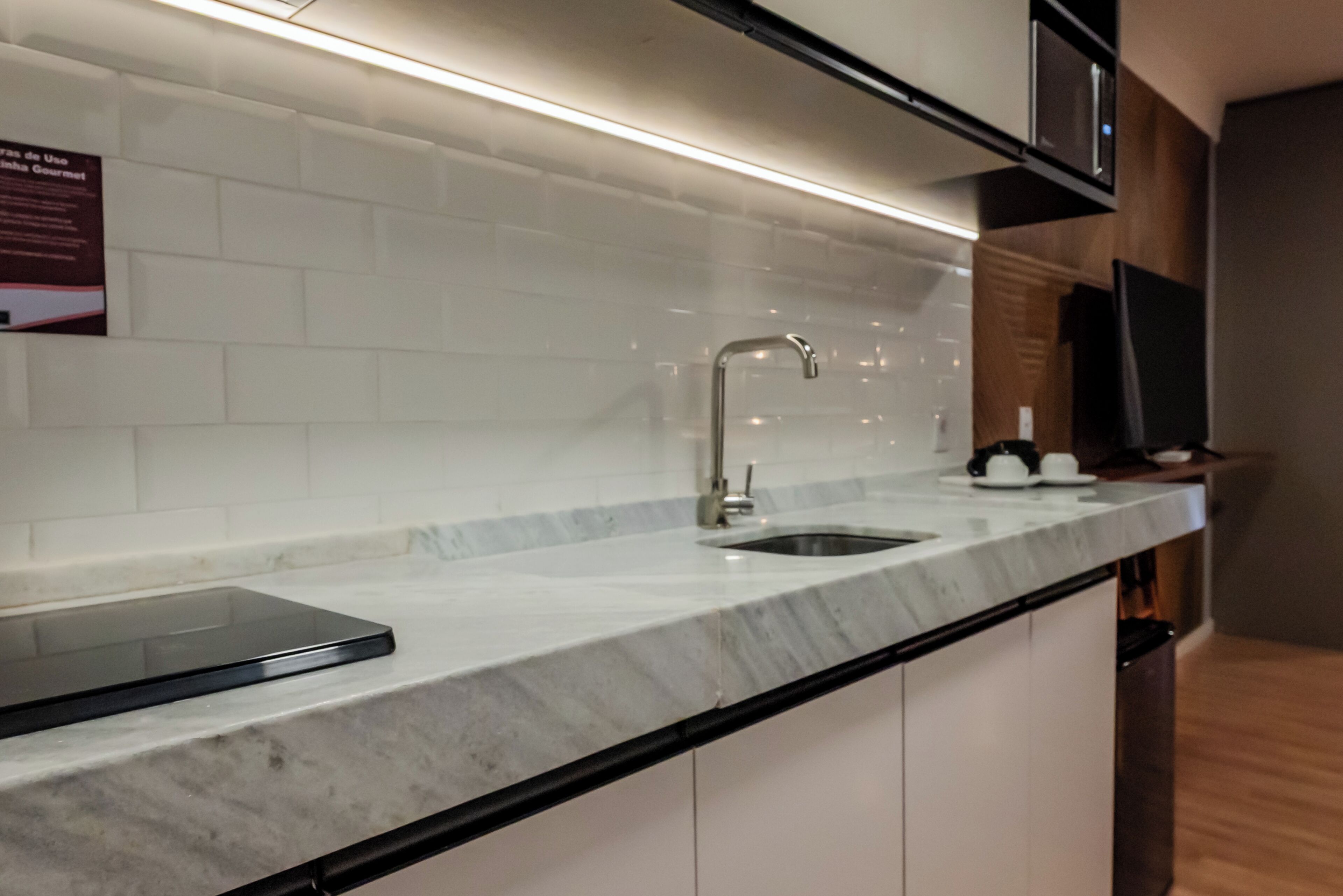 Una cocina con encimera de mármol, pileta de acero inoxidable y una tableta negra.