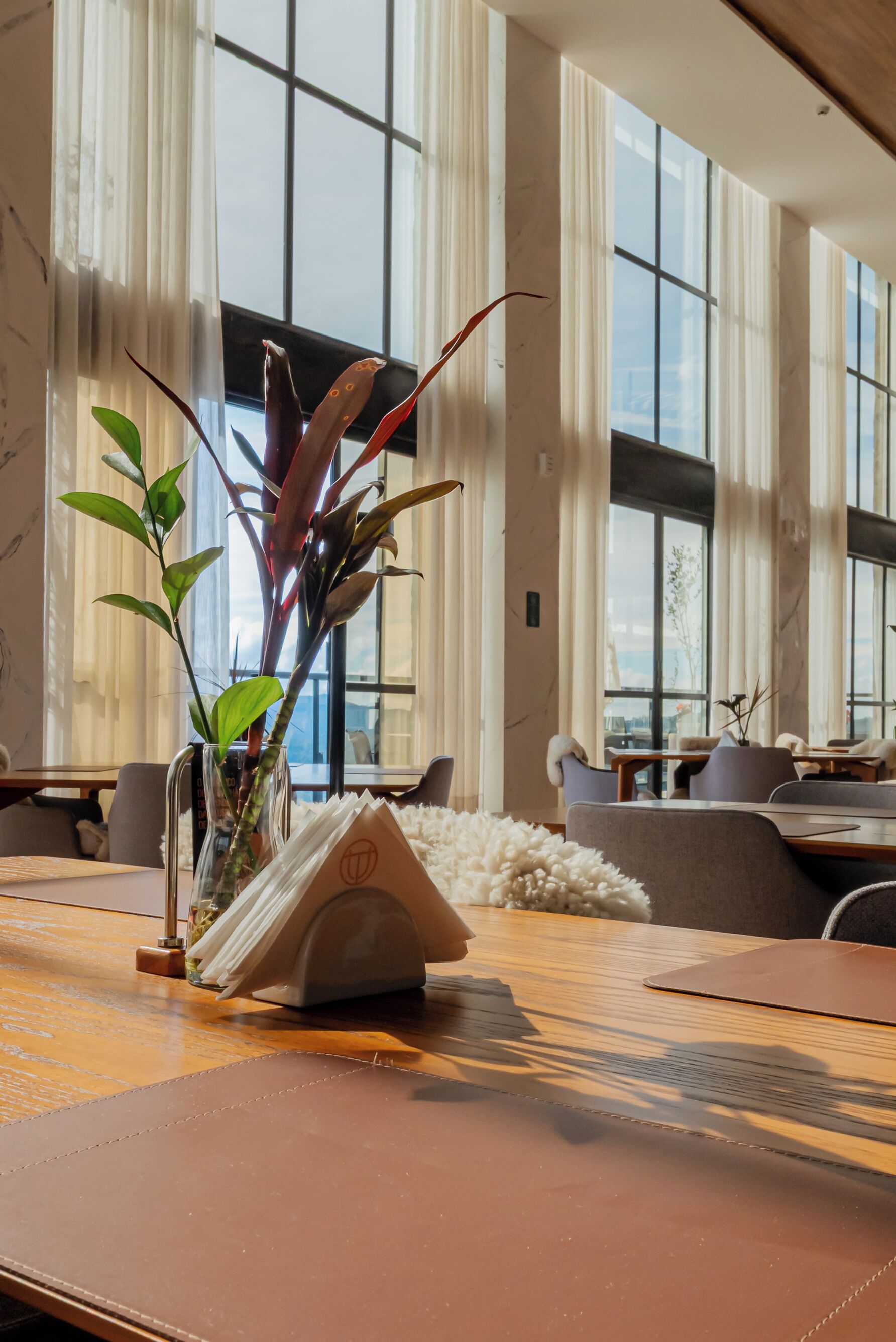 Un comedor con una mesa, sillas, un florero con plantas y un atril para el menú.