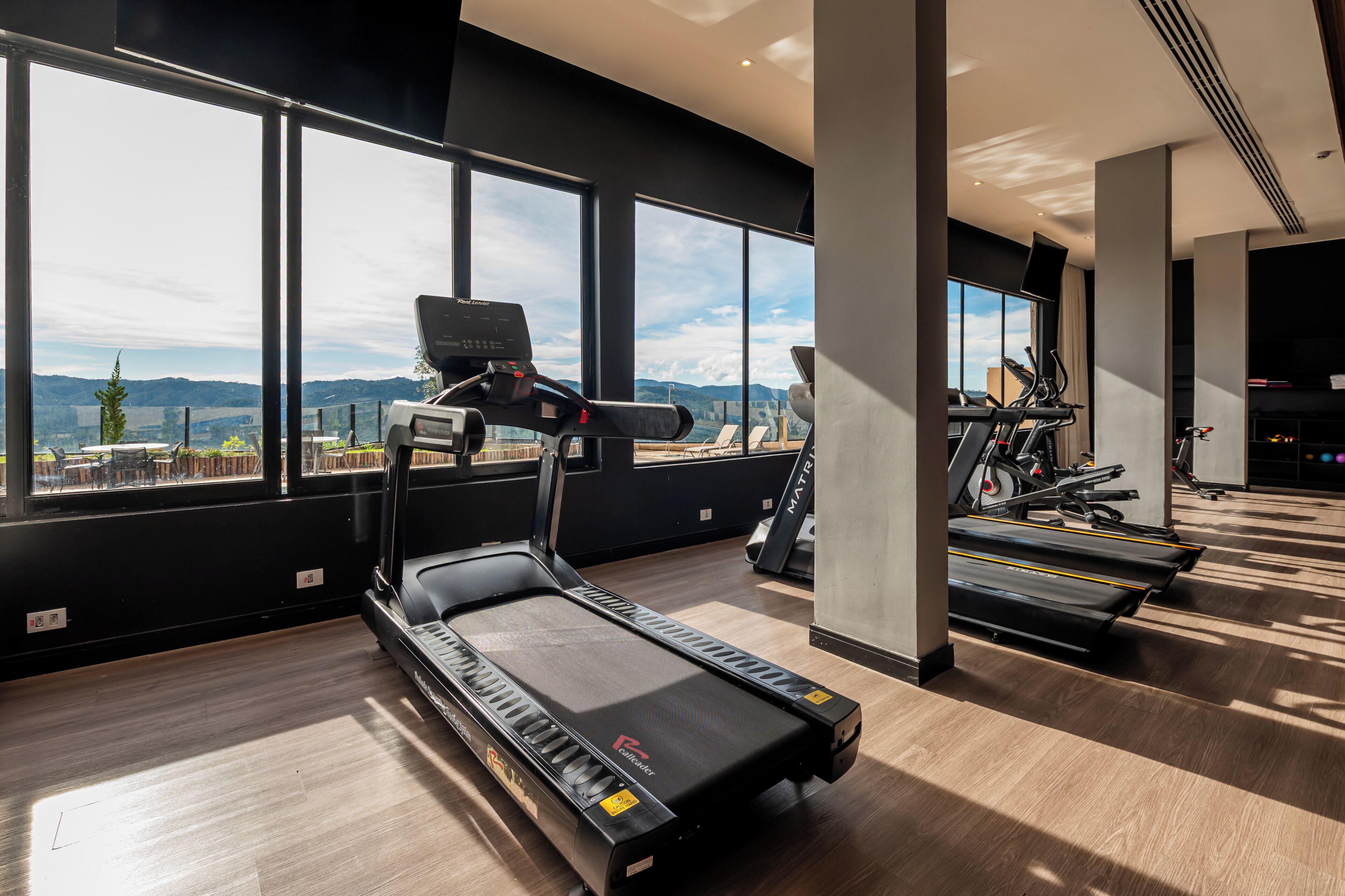 A gym with treadmills, exercise bikes, and a large window with a mountain view.