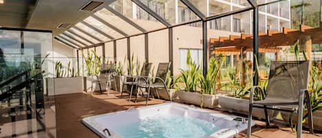 A rooftop terrace with a hot tub, outdoor seating, and a view of the building's balconies.