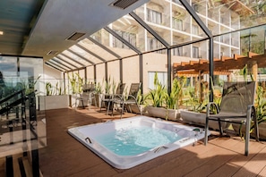 Une terrasse sur le toit avec un jacuzzi, des sièges d’extérieur et une vue sur les balcons de l’immeuble.
