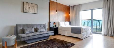 Et moderne soveværelse med en sofa, en seng, et lille natbord, et tæppe og et stort vindue med gardiner.