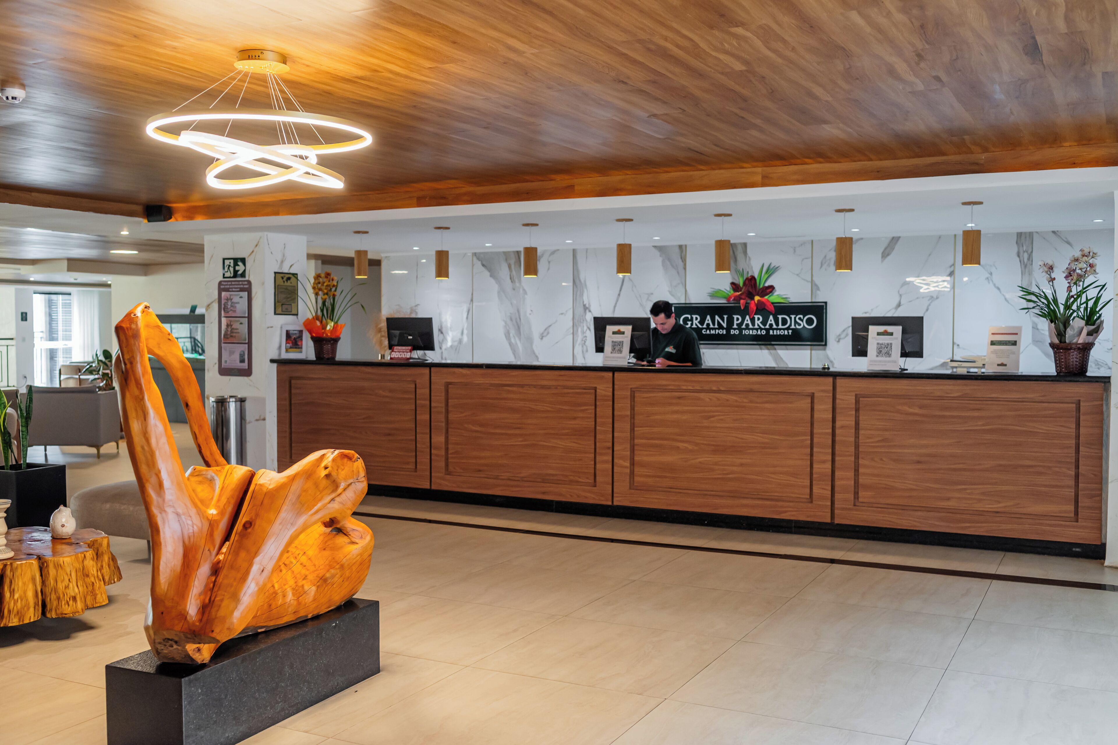 A reception desk with a wooden finish, a modern light fixture, and a sign for Gran Paradiso.