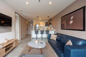 A modern living room with a blue sofa, a coffee table, and a TV mounted on the wall. - lEPl Mordern 1bd Apt W/Ac, Pool, Gym in Medellin (Medellín)