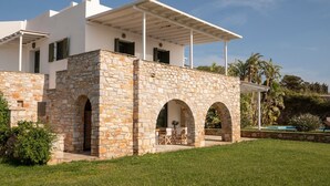 A modern house with stone walls, a covered patio, and a pool.