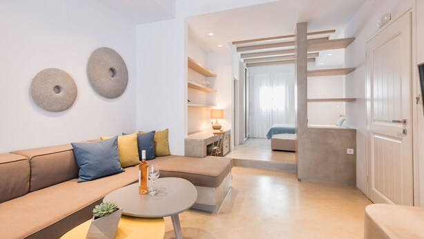 A modern living room with a sofa, a coffee table, and a lamp. There is a door leading to another room. - Michael Zeppos Studio 1, Naousa (Naousa)