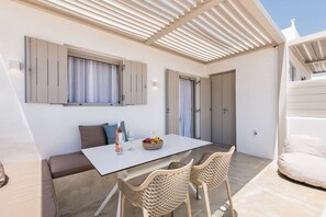 A modern outdoor dining area with a table, chairs, and a sofa.