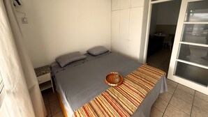 Ett sovrum med en säng, kuddar, ett sängbord, en garderob och en skjutdörr i glas som leder ut till en balkong.