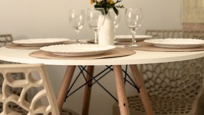 Ett runt matbord med vita tallrikar, en vas med blommor och vinglas.
