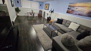 A living room with a sofa, coffee table, and a dining area with chairs and a table.