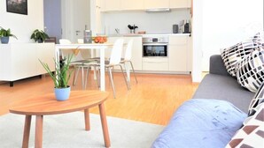 Un salon moderne avec une table à manger, un canapé et une cuisine en arrière-plan.