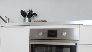 Une cuisine avec des armoires blanches, un four en acier inoxydable et un four à micro-ondes.
