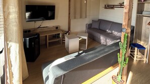 Una sala de estar con sofá, televisor, vigas de madera y una planta en maceta.