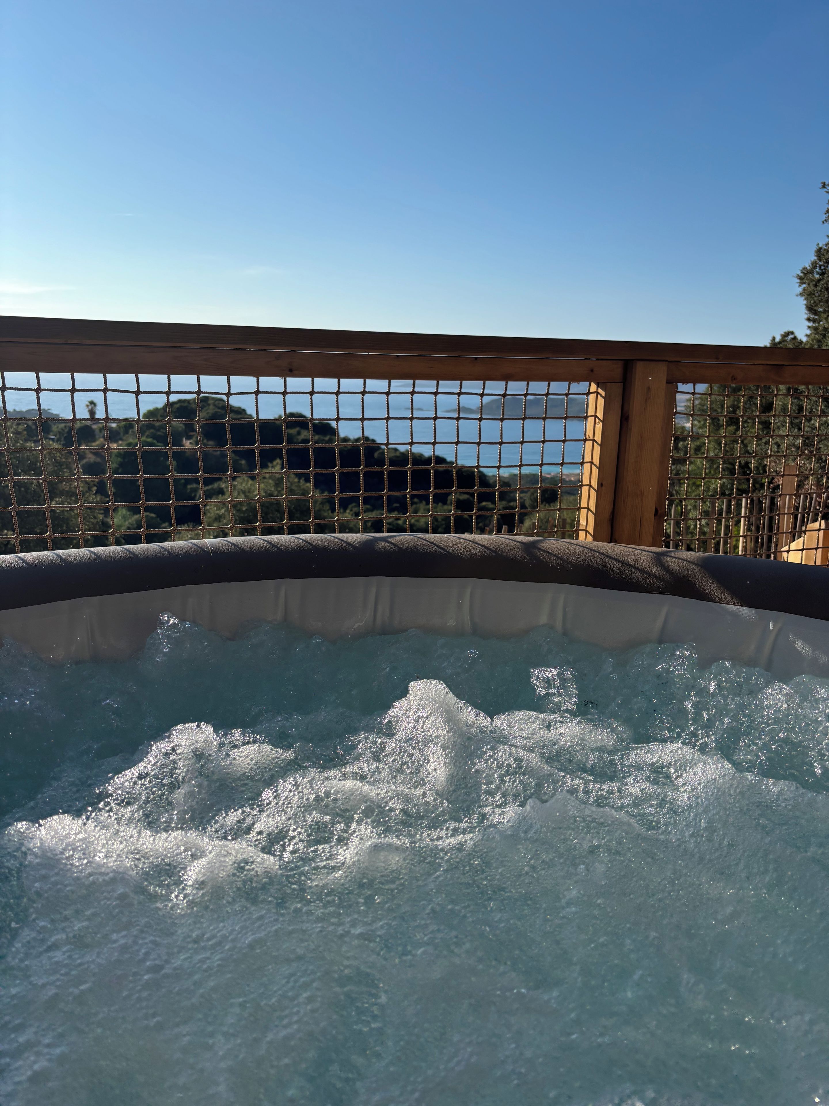 Ein Whirlpool mit Holumrandung und Blick auf eine gebirgige Landschaft.