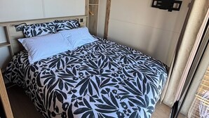 Un dormitorio con cama, una lámpara colgante y una ventana con cortinas.