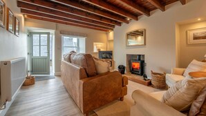 A cozy living room with a fireplace, leather sofas, and wooden beams on the ceiling. - Charming Countryside Cottage Yorkshire Dales (Richmond)