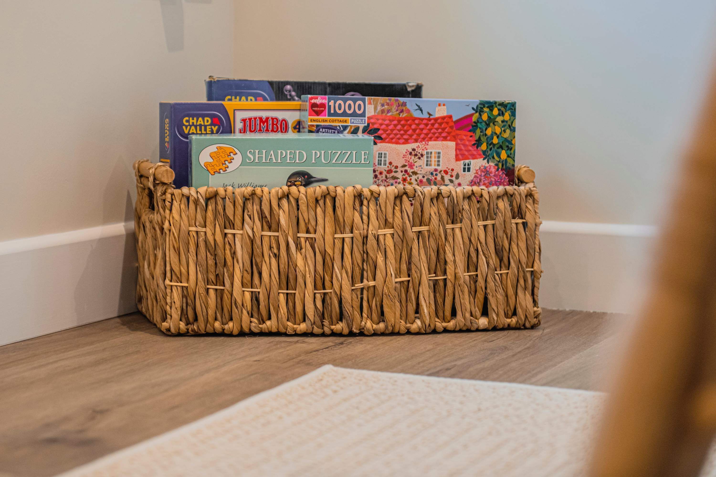 A woven basket containing various puzzle boxes on a wooden floor.