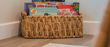 A woven basket containing various puzzle boxes on a wooden floor.