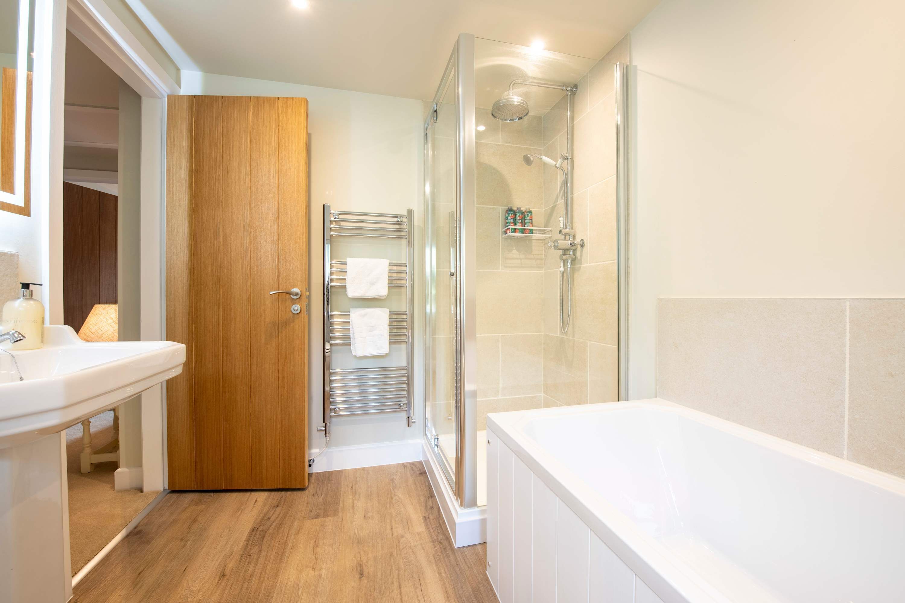 Een badkamer met een douche, een bad, een wastafel en een handdoekrek.