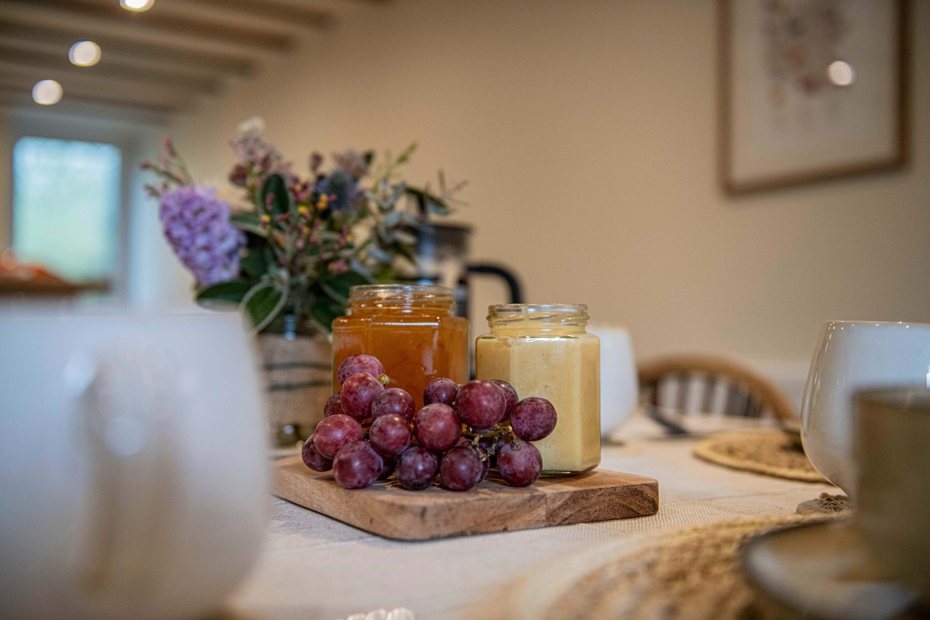 A table with jars of honey, a bunch of grapes, and a glass of white wine.
