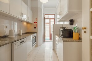 A modern kitchen with white cabinets, a dishwasher, an oven, and a microwave. - City Center Terrace Apartment by Vacationy (Porto)