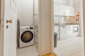 A laundry area with a washing machine, a drying rack, and a trash bin. - City Center Terrace Apartment by Vacationy (Porto)