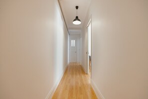 A narrow hallway with wooden flooring, white walls, and a door at the end. - City Center Terrace Apartment by Vacationy (Porto)