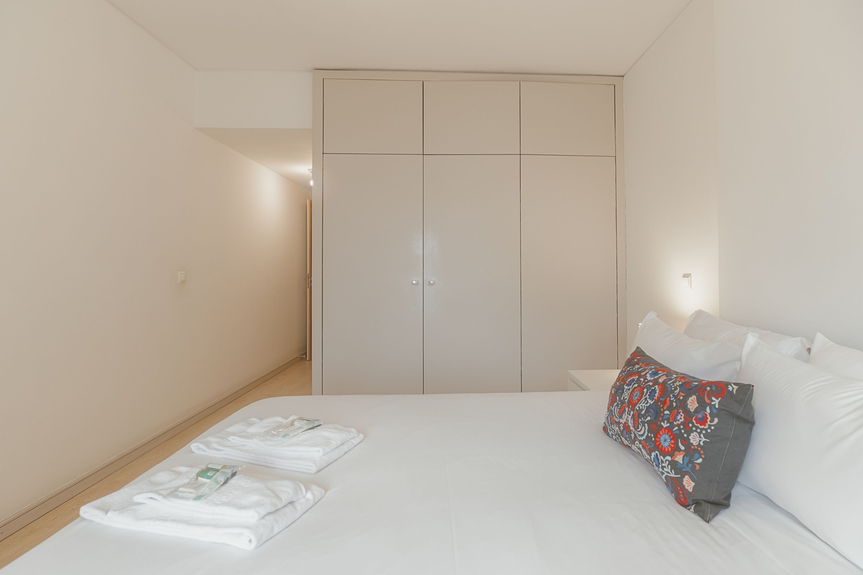 Een slaapkamer met een bed, een kledingkast en een nachtkastje.
