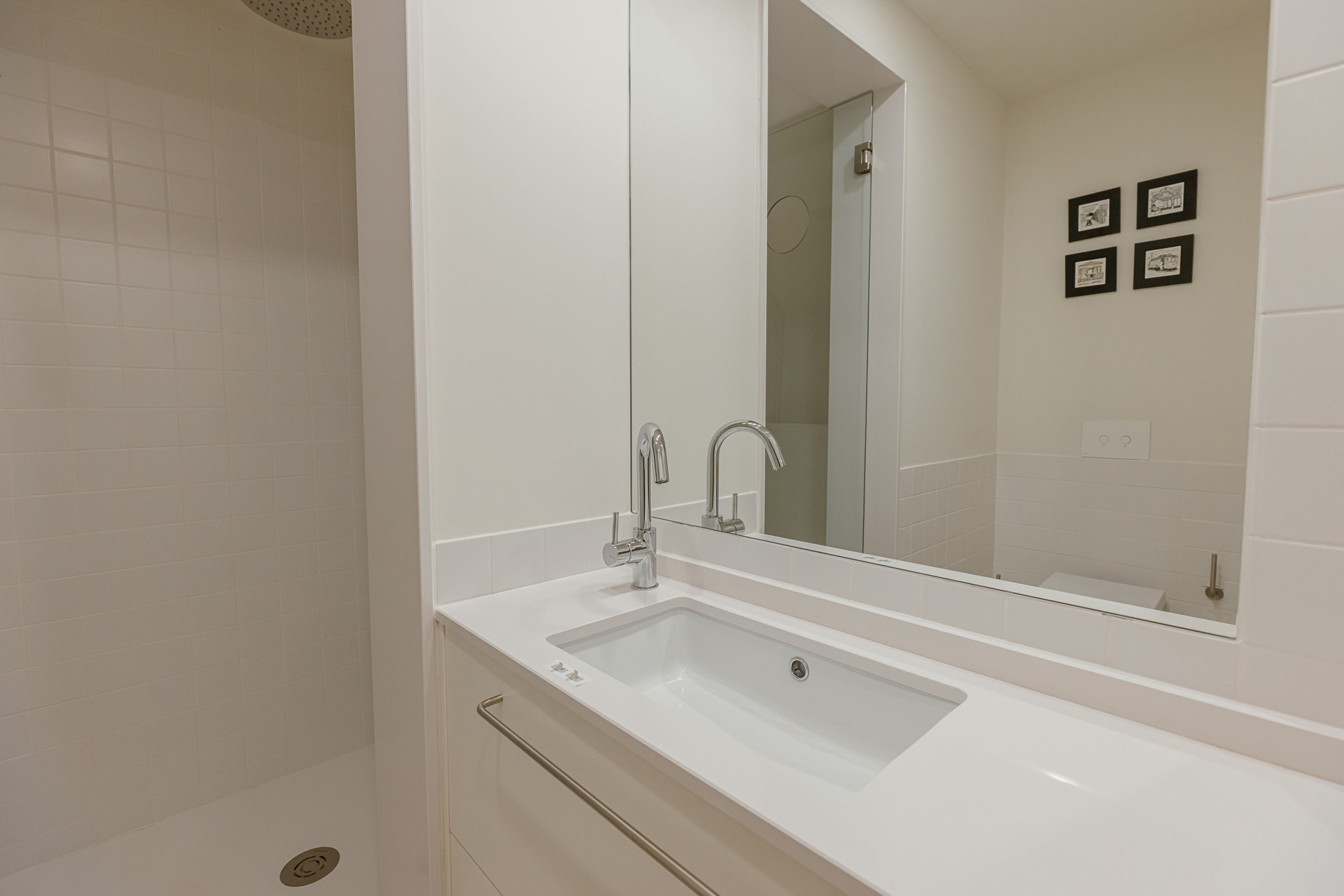 Un baño con lavamanos blanco, espejo y ducha.