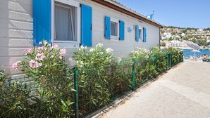 A coastal building with blue shutters, a visible balcony, and a view of the sea and town. - Mobile Home in Rabac With Shared Pool (Labin)