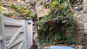 A stone wall with a wooden gate and a small garden area with a bench. - Charming Holiday Retreat in Derbyshire Countryside (Matlock)