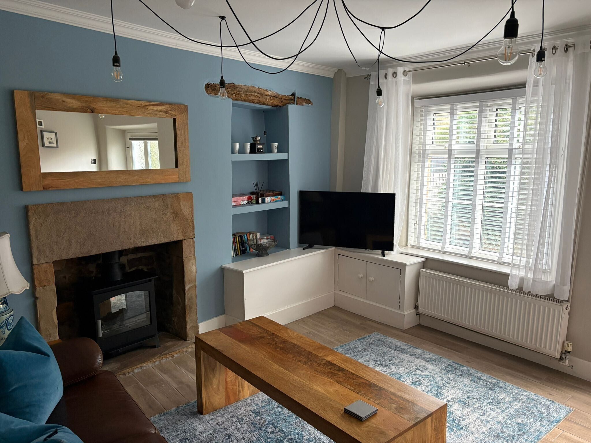 A living room with a fireplace, TV, and a window with blinds.