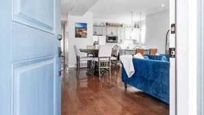 Un interior modern amb zona de menjador, cuina i un sofà blau.