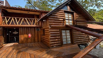 A log cabin with a wooden deck, a balcony, and a fire extinguisher.