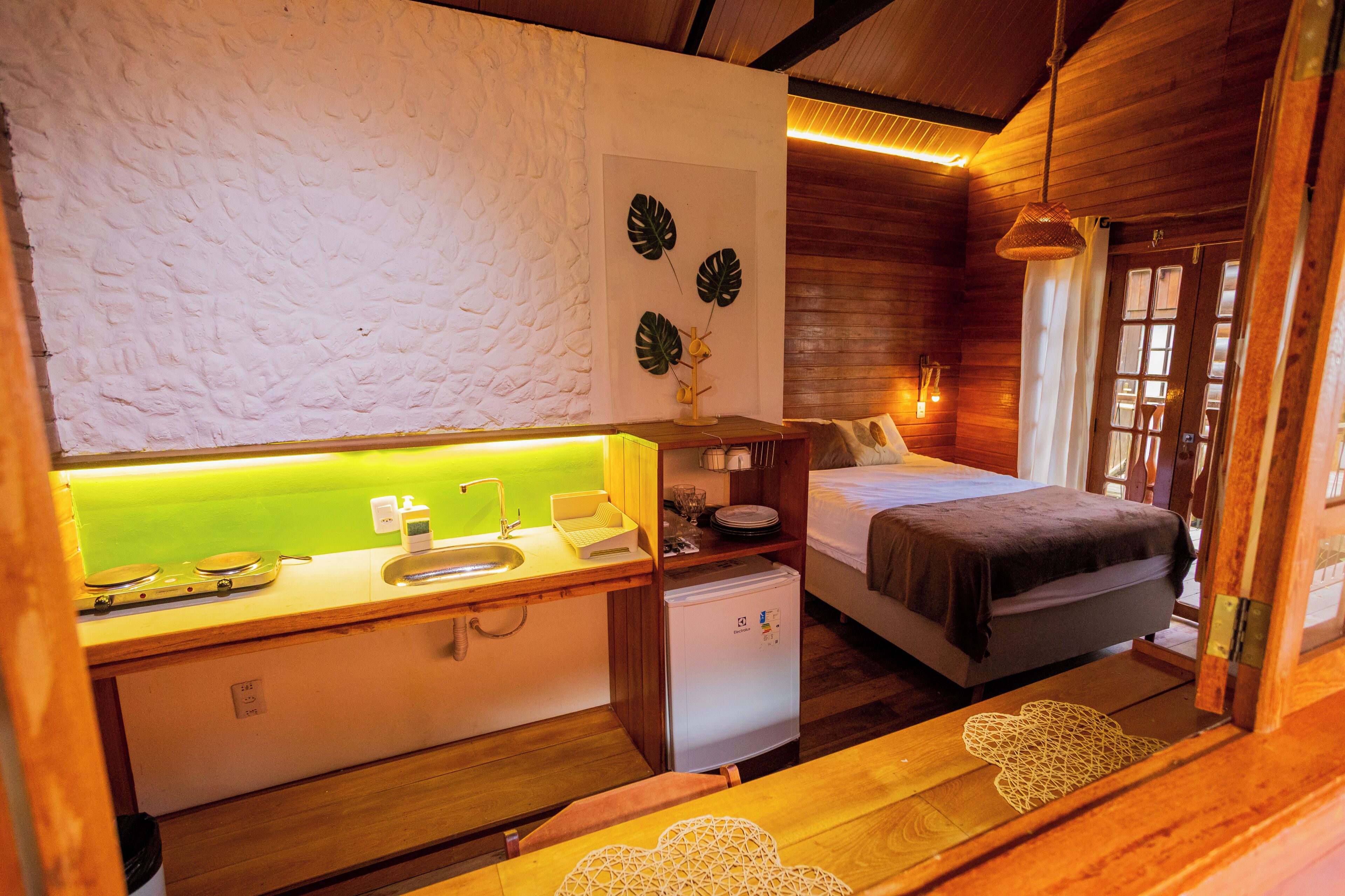 A compact room with a bed, a small kitchenette, and a bathroom.