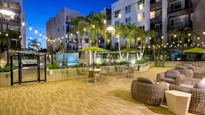 Eine Außenpatio-Terrasse mit Sitzgelegenheiten, Palmen und Lichterketten.